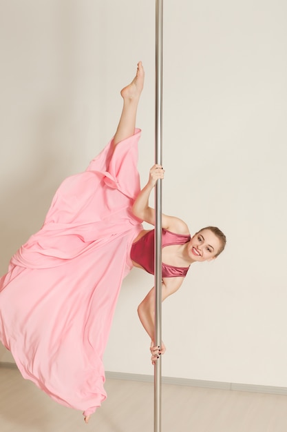 Фото Женщина poledance растягивается в красивом розовом платье