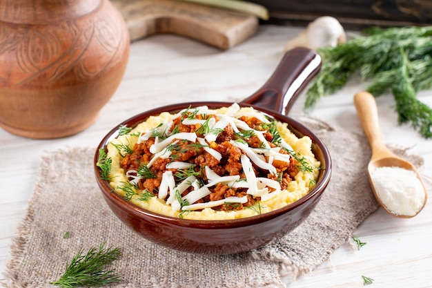 Polenta boiled cornmeal with meatbased sauce ragu alla bolognese on a white wooden table