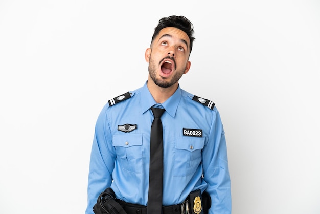 Police caucasian man isolated on white background looking up and with surprised expression