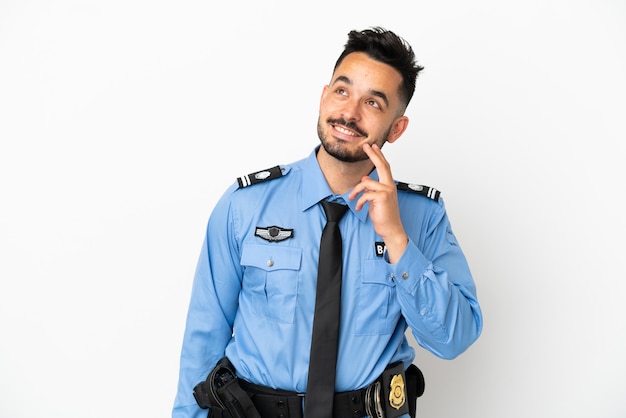 Police caucasian man isolated on white background thinking an idea while looking up