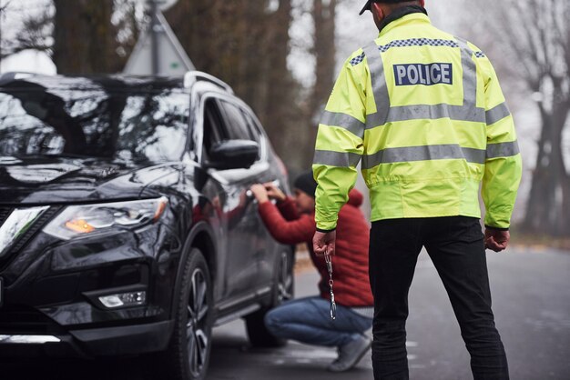 緑の制服を着た警官が道路で自動車の盗難を捕まえた。