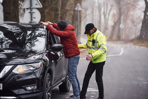 L'ufficiale di polizia in uniforme verde ha scoperto un furto d'auto per strada.