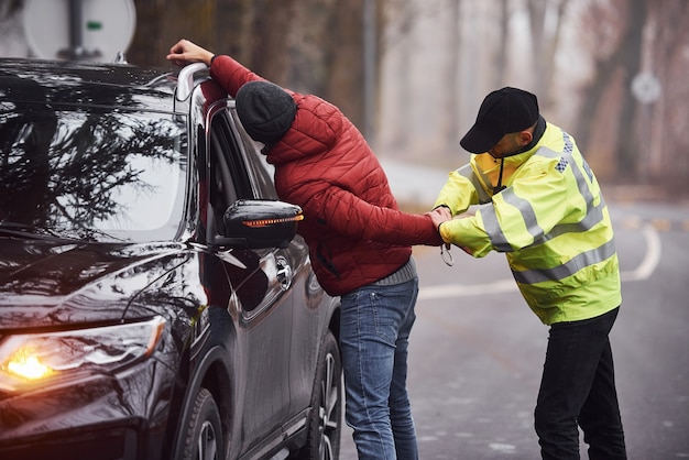 Police officer in green uniform caught automobile theft on the road.