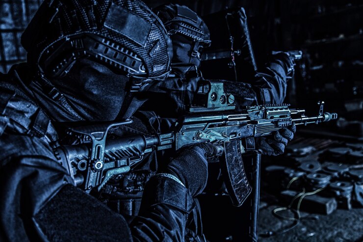 警察の特殊部隊、テロ対策の戦術チームの戦闘機、反麻薬襲撃の弾道シールドのカバーの下で前進しながら銃を狙う民間警備会社の警備員、彩度の低い