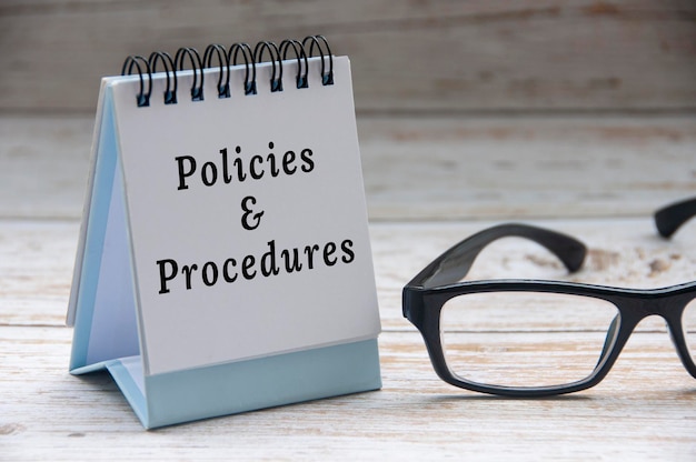 Policies and procedures text on notepad with glasses on white wooden cover background