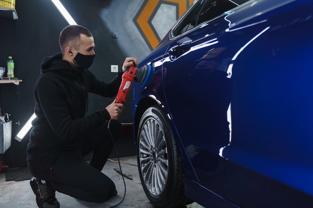 Polijsten auto na het schilderen. Detaillering van de auto van buitenaf. Apparaat voor polijsten in handen