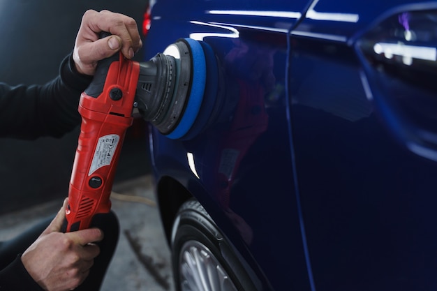 Polijsten auto na het schilderen. Detaillering van de auto van buitenaf. Apparaat voor polijsten in handen