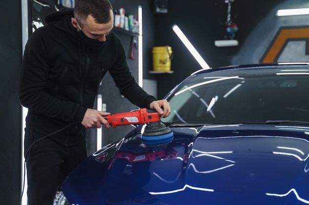 Foto polijsten auto na het schilderen. detaillering van de auto van buitenaf. apparaat voor polijsten in handen