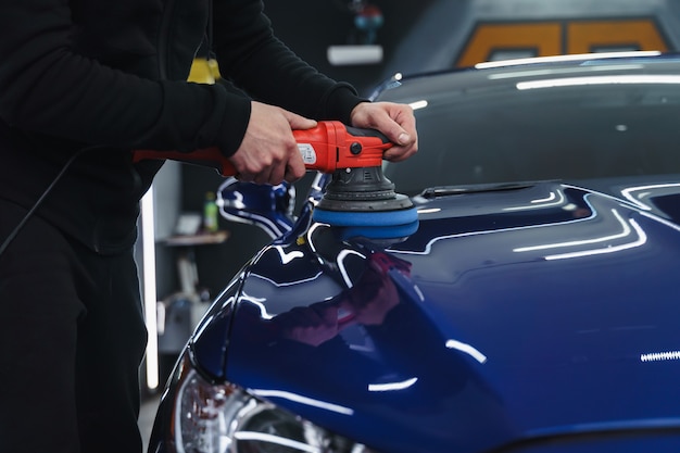 Foto polijsten auto na het schilderen. detaillering van de auto van buitenaf. apparaat voor polijsten in handen