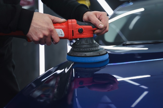 Foto polijsten auto na het schilderen. detaillering van de auto van buitenaf. apparaat voor polijsten in handen