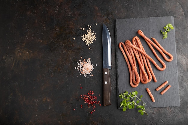 Polish smoked sausage kabanos on a slate cutting board on black concrete background Top view copy space