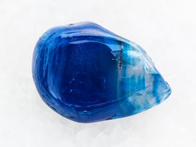 Polished blue toned agate gemstone on white marble