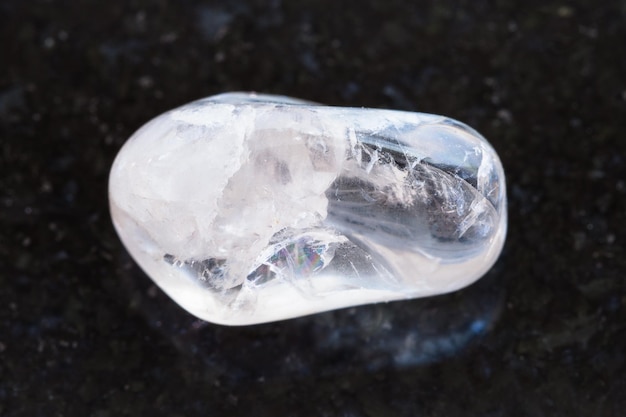 Polished clear quartz gemstone on dark background