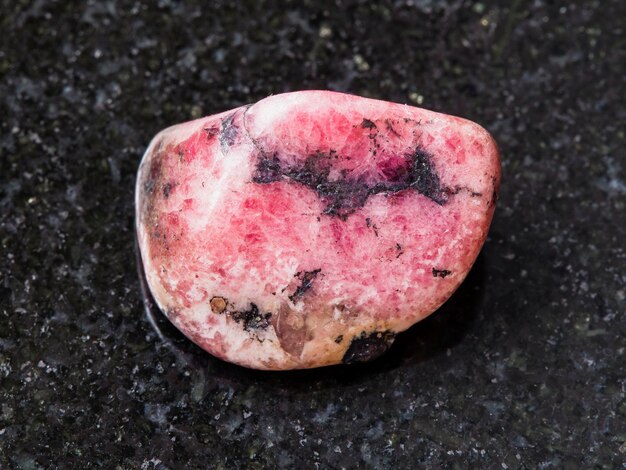 Polished pink rhodonite gem stone on dark