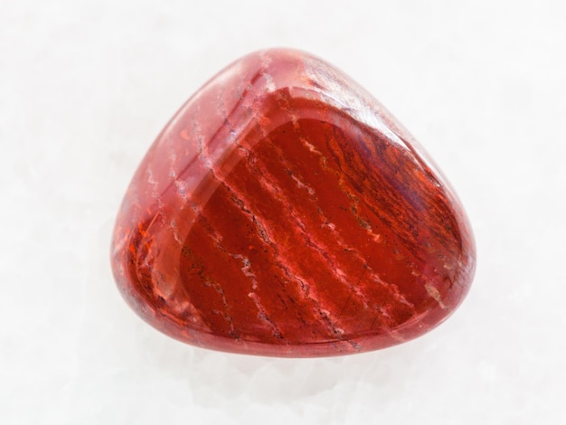 Polished red jasper gem stone on white marble