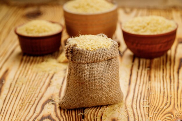 Полированный вареный рис в мисках и мешках на деревянном фоне Фото высокого качества