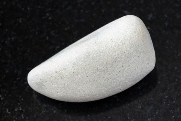 polished white limestone gemstone on dark