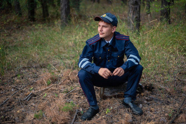 Politieagent zit op het gras in het bos en denkt