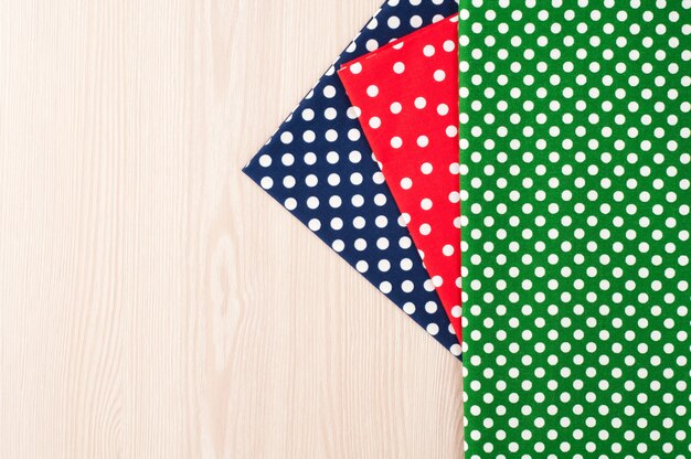 Polka dot fabric for sewing and needlework on wooden background. top view