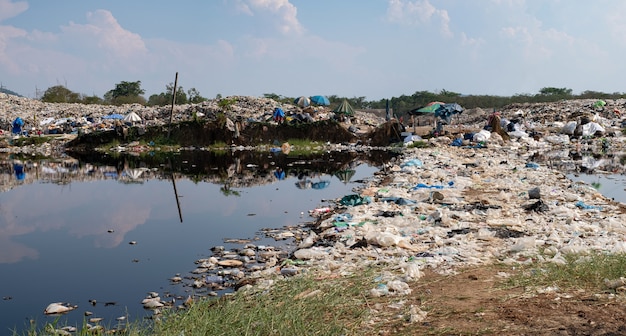 Polluted water and mountain large garbage pile and pollution\
pile of stink and toxic residue