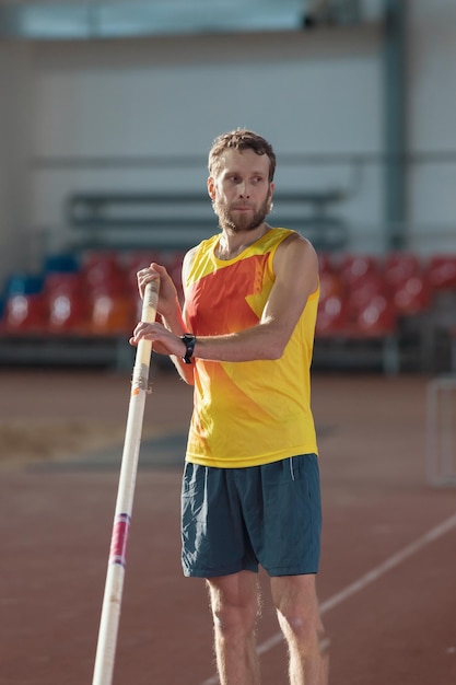 Polsstokhoogspringen binnenshuis een man in geel shirt die op de baan staat met een paalsportstadion