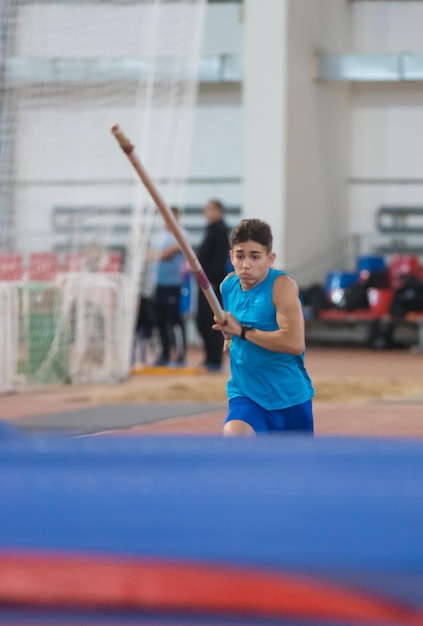 Polsstokhoogspringen binnenshuis man in een blauw shirt die een paal vasthoudt