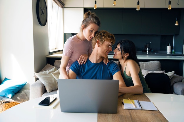 Photo polyamorous couple at home working on laptop