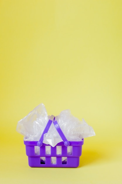 Polythene bags in shopping basket on yellow background