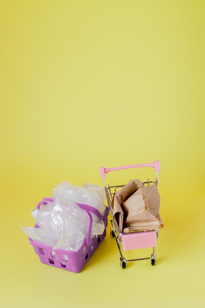 Polythene and paper bags in a shopping basket on a yellow background