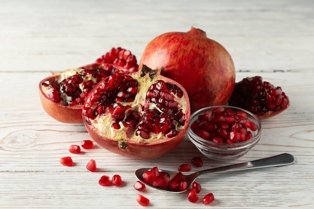 Pomegranate, bowl and spoon on wooden, close up