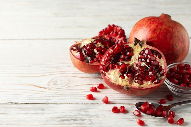 Pomegranate, bowl and spoon on wooden, close up