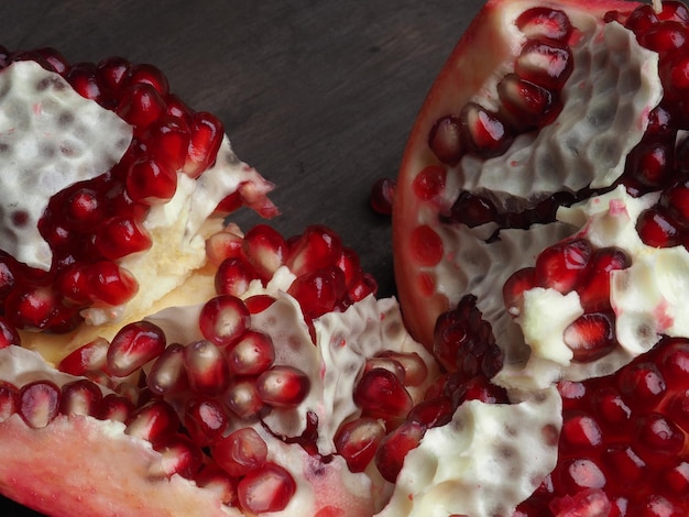 A pomegranate cut in half and the seeds are white on the bottom.