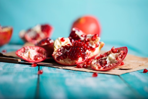 Pomegranate fruit on a cyan wooden surface. Closeup