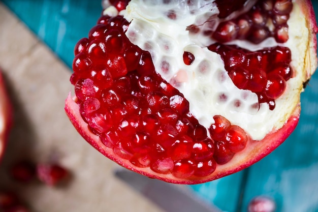 Pomegranate fruit on a cyan wooden surface. Closeup