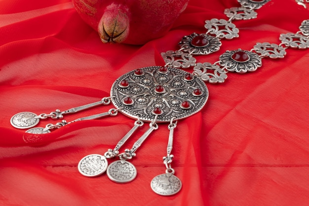 Pomegranate fruit with turkish jewellery and open pomegranate on an red, side view