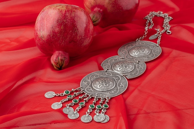 Pomegranate fruit with turkish jewellery and open pomegranate on an red, side view