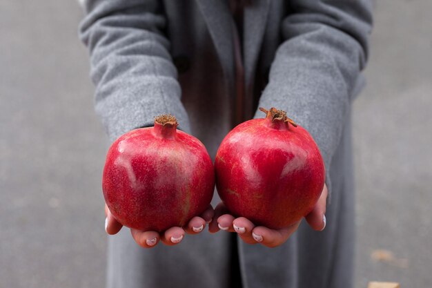 Photo pomegranate fruits the girl holds a fresh ripe ruby pomegranate in her palms