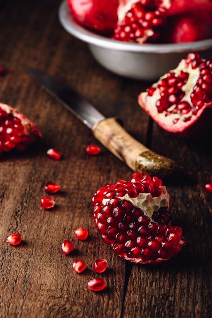 Pomegranate fruits with knife on rustic wooden surface