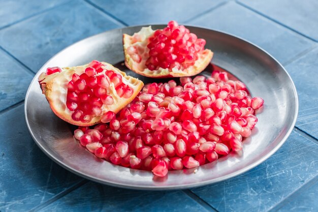 Pomegranate grains on a metal plate, close-up stock photo in simple rustic style