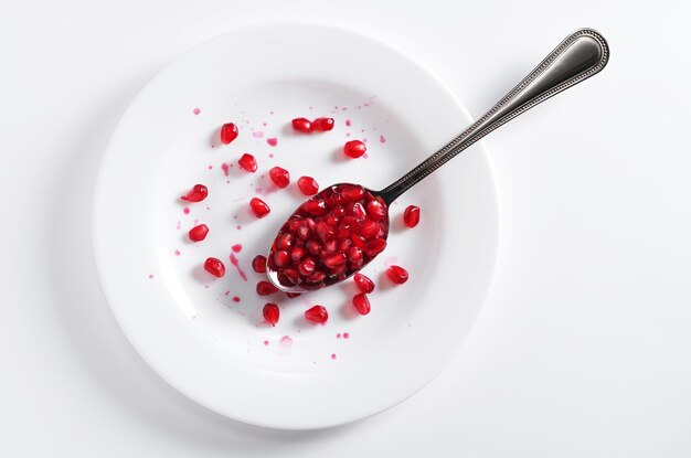 Pomegranate grains in a spoon and drops of juice