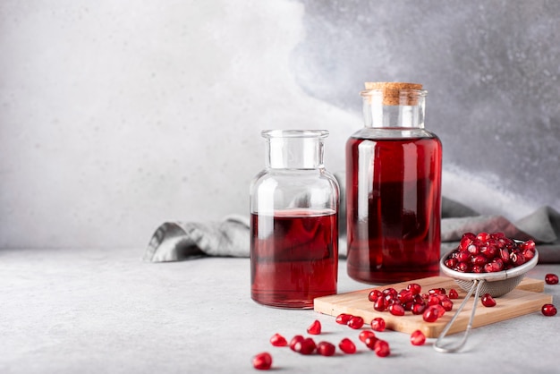 Pomegranate juice in glass bottles and pomegranate grains on a wooden board