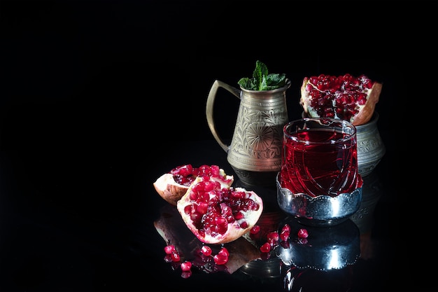 Pomegranate juice in a glass and pomegranate slices on a dark surface. . Still life.