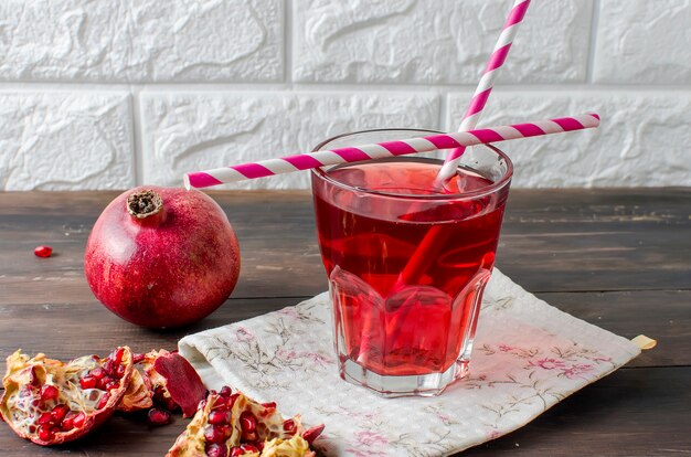 Pomegranate juice in glass and pomegranates  on dark old wooden background