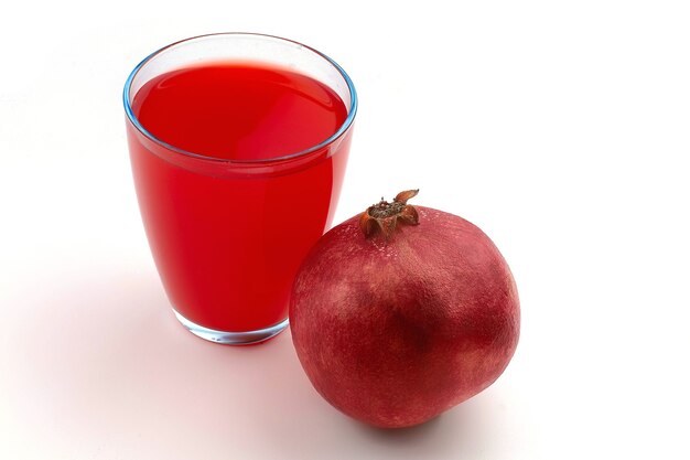 Pomegranate and juice in a glass on a white surface