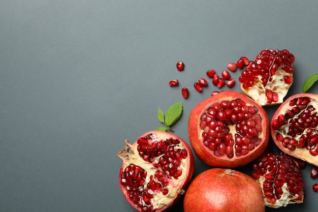 Photo pomegranate, leaves and seeds on gray, top view