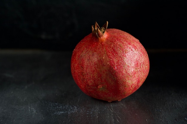 The pomegranate lies on a dark concrete table.