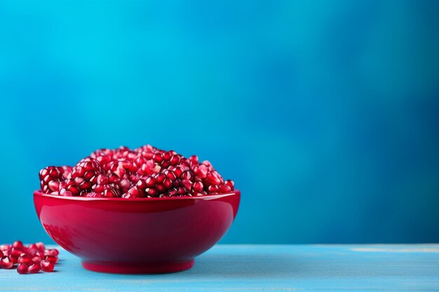 pomegranate seeds in a bowl on blue free space