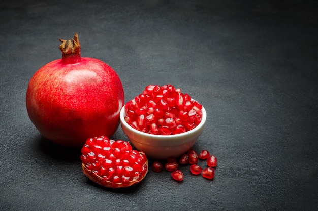 Pomegranate and seeds on dark concrete table