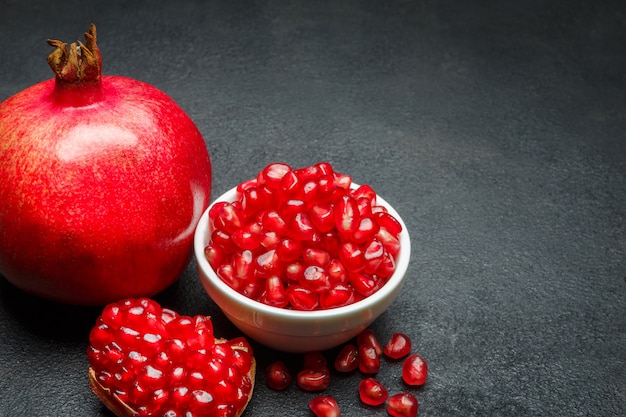 Pomegranate and seeds on dark concrete table