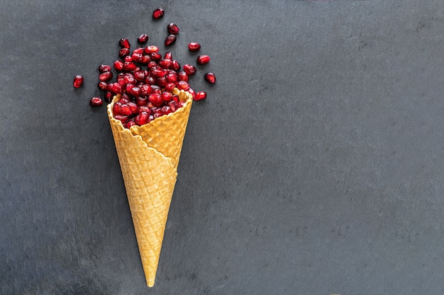 Pomegranate seeds in waffle cone on dark